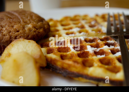 Cialde, Banana muffin al cioccolato alla griglia e patate servita per prima colazione. Lo zucchero in polvere viene spruzzata sul disegno waffle. Foto Stock