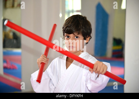 Arti marziali boy tenendo due bastoni rosso denominato ka-li - bastoncini di combattimento Foto Stock