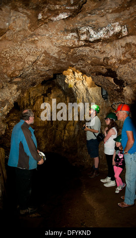 Gruppo familiare di turisti ad esplorare Smoo Cave Indossare copricapi rigidi Foto Stock