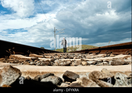 Uomo che cammina su binari ferroviari Foto Stock