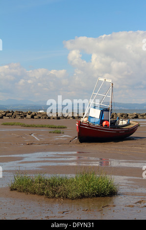 Un rosso, bianco e blu barca da pesca in appoggio sulle sabbie della baia di Morecambe durante la bassa marea. Foto Stock