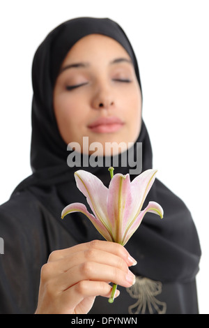 Bella donna araba che indossa un hijab odorare un fiore isolato su uno sfondo bianco Foto Stock