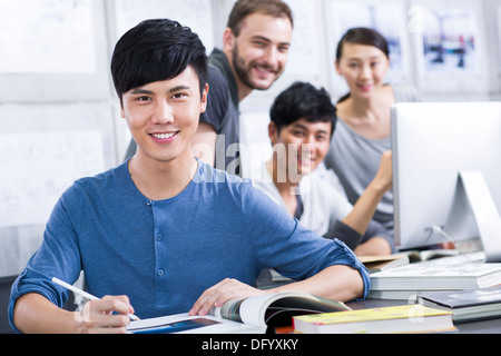 Giovane uomo con il suo team in ufficio Foto Stock
