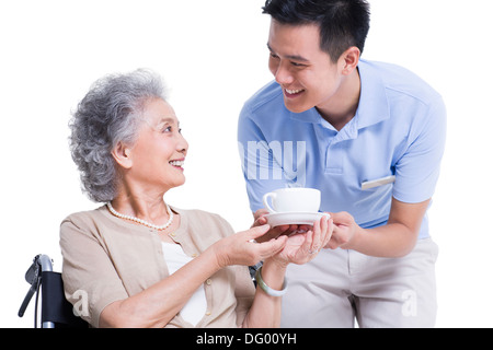 Maschio lavoratore infermieristico che serve tè al senior donna Foto Stock