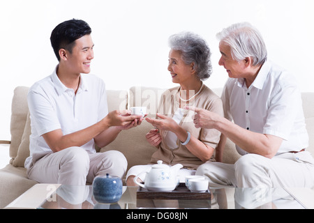 La famiglia felice avente il tè e in chat Foto Stock