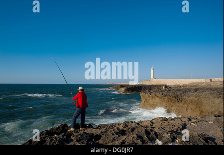 Pescatore. Sullo sfondo il faro di Rabat ( Marocco) Foto Stock