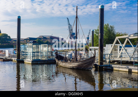 Un vecchio clinker costruito la barca a vela è legata sul fiume Clyde di un ferry terminal, grandi gru industriali in background Foto Stock