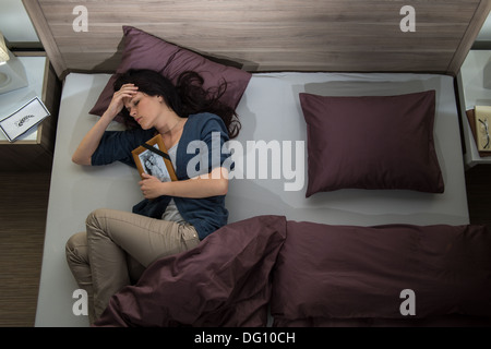 Lonely donna giaceva a letto manca il suo marito morto Foto Stock