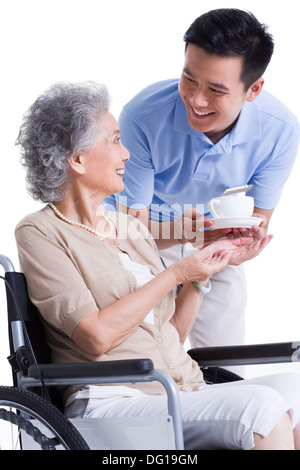 Maschio lavoratore infermieristico che serve tè al senior donna Foto Stock