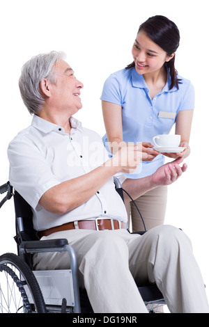 Femmina lavoratore infermieristico che serve tè al senior donna Foto Stock