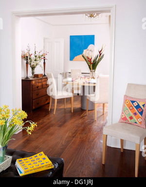 Vista attraverso le doppie porte di sala da pranzo con spogliato parquet in legno e imbottiti sedie bianche e tavola circolare Foto Stock