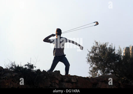 Ramallah, West Bank, Territorio palestinese . Undicesimo oct, 2013. Un manifestante palestinese utilizza un slingshot per scagliare pietre durante gli scontri con i soldati israeliani in Betunia vicino al West Bank città di Ramallah il 11 ottobre 2013. Credito: ZUMA Press, Inc./Alamy Live News Foto Stock