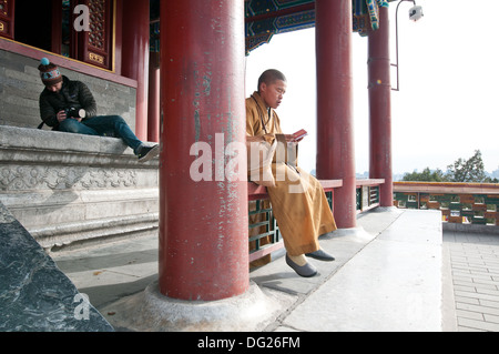 Giovane monaco buddista pregando in Wanchun ting Pavilion (Padiglione dell'eterna primavera) nel Parco Jingshan, Pechino, Cina Foto Stock