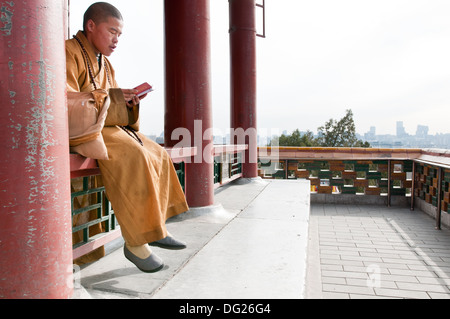 Giovane monaco buddista pregando in Wanchun ting Pavilion (Padiglione dell'eterna primavera) nel Parco Jingshan, Pechino, Cina Foto Stock