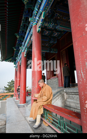 Giovane monaco buddista pregando in Wanchun ting Pavilion (Padiglione dell'eterna primavera) nel Parco Jingshan, Pechino, Cina Foto Stock