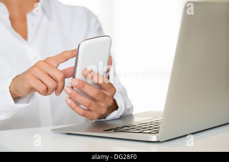 Laptop femmina cellulare dito scrivania indoor Foto Stock