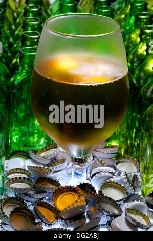 Bicchiere di birra con bottiglie vuote e tappi Foto Stock