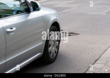 Asfalto di fori sul fondo stradale. Auto in un movimento. Foto Stock