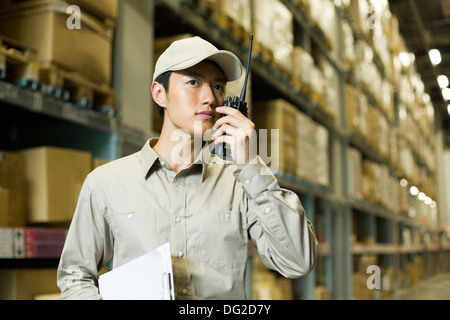 Logistica di giovane personale usando un walkie-talkie in magazzino Foto Stock