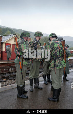 1940 esercito guerra man a Levisham. North Yorkshire, Regno Unito. 11 ottobre, 2013. Stazione tedesca protezioni o Feldgendarmerie, la polizia militare unità, presso la "Ferrovia in tempo di guerra' Nord nello Yorkshire Moors Railway (NYMR) evento a Levisham stazione ferroviaria in condizioni di tempo inclemente sul weekend 12 -13 ottobre 2013. Stazione Levisham era decorato con periodo di poster e insegne francesi durante il (NYMR) "Weekend di guerra" di diventare 'Le Visham' nel nord della Francia. La raccolta, una ricreazione di un villaggio francese occupata dai Tedeschi durante la Seconda Guerra Mondiale, la II Guerra Mondiale, seconda guerra mondiale, durante la seconda guerra mondiale, WW2 truppe. Foto Stock