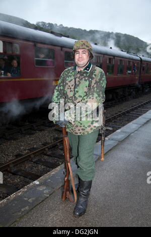 1940 esercito guerra man a Levisham. North Yorkshire, Regno Unito. 11 ottobre, 2013. Kevin Armstrong da Londra come un Waffen SS soldato tedesco presso la "Ferrovia in tempo di guerra' Nord nello Yorkshire Moors Railway (NYMR) evento a Levisham stazione ferroviaria in condizioni di tempo inclemente sul weekend 12 -13 ottobre 2013. Stazione Levisham era decorato con periodo di poster e insegne francesi durante il (NYMR) "Weekend di guerra" di diventare 'Le Visham' nel nord della Francia. La raccolta, una ricreazione di un villaggio francese occupato dalla Seconda Guerra Mondiale, la II Guerra Mondiale, seconda guerra mondiale, durante la seconda guerra mondiale, WW2 truppe tedesche, Foto Stock