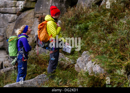 Due coloratissimi arrampicatori a bordo Stanage, Parco Nazionale di Peak District, England Regno Unito discutendo quale percorso per fare la prossima. Foto Stock