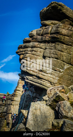 Maschio di rocciatore persona facendo un tacco gancio sul nocciolo del volo diretto di contrafforte, Stanage, Peak District, REGNO UNITO Foto Stock