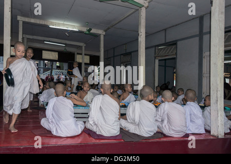 Il debuttante monaci di mangiare il loro pasto di mezzogiorno nella sala da pranzo, Monastero Mahagandayon, Amarapura, Myanmar Foto Stock