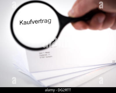 Lettera con un contratto di vendita rappresentato da un vetro di ingrandimento Foto Stock