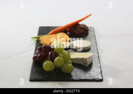 Selezione di formaggi serviti su nero ardesia Foto Stock