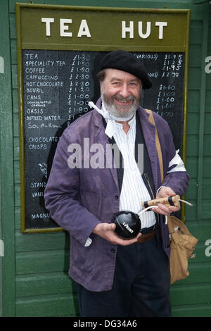 Capanna di tè e menu a Levisham. North Yorkshire, Regno Unito. 11 ottobre, 2013. Signor Mike Thompson, Terzo Reich Luftwaffe operaio di fabbrica tenendo una bomba presso la "Ferrovia in tempo di guerra' Nord nello Yorkshire Moors Railway (NYMR) evento a Levisham stazione ferroviaria in condizioni di tempo inclemente sul weekend 12 -13 ottobre 2013. Stazione Levisham era decorato con periodo di poster e insegne francesi durante il (NYMR) "Weekend di guerra" di diventare 'Le Visham' nel nord della Francia. La raccolta, una ricreazione di un villaggio francese occupato dalle truppe tedesche, essendo parte del 'Allo Allo'-style spensierati e divertenti dell'umore. Foto Stock