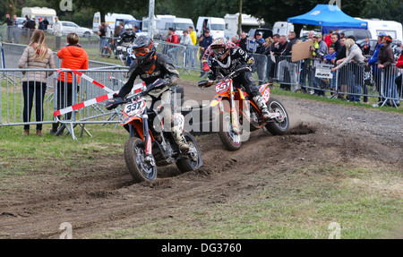 Supermoto piloti di prendere una curva sul lato sporco della pista. Incentrato sul ciclista al centro dell'immagine. Foto Stock