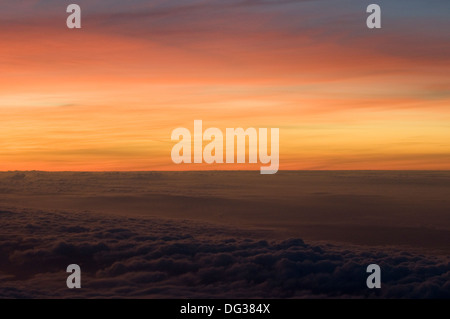 Golden arancione tramonto sopra le nuvole visto dalla finestra aereo sul viaggio in Rwanda dal Regno Unito Foto Stock