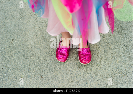 Ragazza giovane indossando abiti colorati e scintillanti scarpe rosa, ad alto angolo di visione Foto Stock