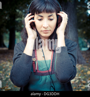 Giovane donna bella ascoltare musica al parco in autunno Foto Stock