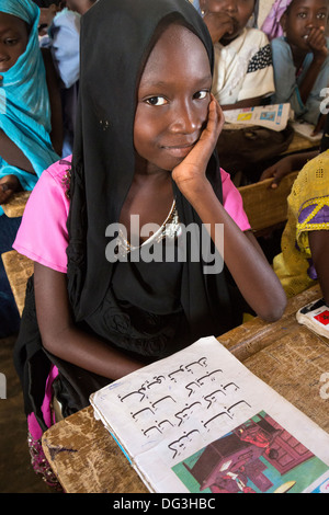 Il Senegal, Touba. Ragazza giovane con il suo lettore di arabo a Al-Azhar madrasa, una scuola di studi islamici. Foto Stock