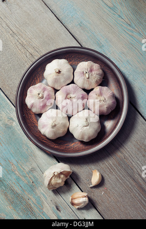 Aglio fresco sulla piastra marrone vintage su sfondo di legno Foto Stock