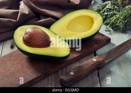 Avocado fresco sul bordo di taglio su sfondo di legno Foto Stock