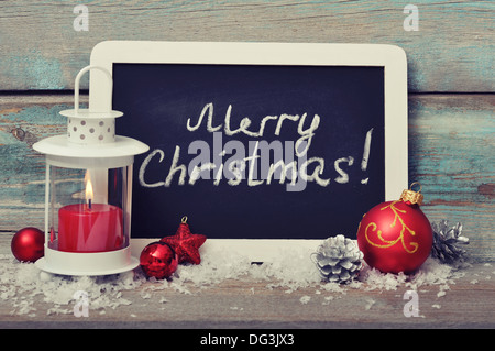 Decorazione di natale con candela in lanterna e incorniciato dalla lavagna su sfondo di legno Foto Stock