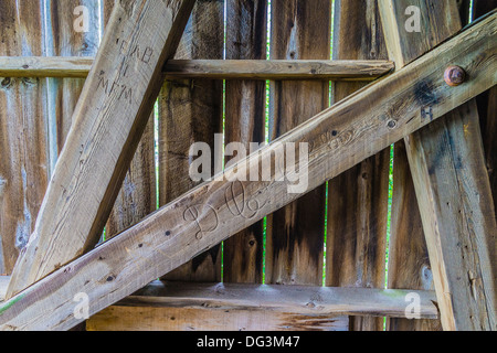 Un close-up dettaglio dei supporti strutturali di una vecchia coperta in legno ponte con le iniziali di persone scolpiti in loro. Foto Stock