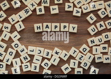 Lettere di plastica da un childrens' ortografia gioco su un tavolo di legno spell 'felice' Foto Stock