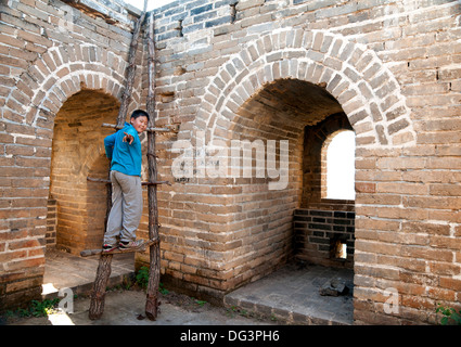 Ragazzo salendo la scala a torre di avvistamento la Grande Muraglia della Cina al Huanghua Foto Stock