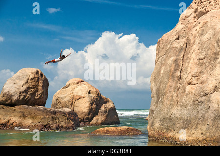 L'uomo immersioni dalla fortezza la parete in un oceano, un ponticello sulla scogliera, Galle, Sri Lanka, Oceano Indiano, Asia Foto Stock