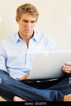 Attraente giovane uomo che lavora sul computer portatile a casa Foto Stock