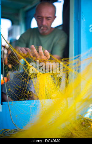 Pulizia del pescatore le sue reti, Mykonos, isole greche, Grecia, Europa Foto Stock