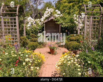 Ornati da giardino in legno arbor con sedile unico e rose rampicanti in Garden cottage, Barnsdale Gardens, Oakham, Rutland, England, Regno Unito Foto Stock