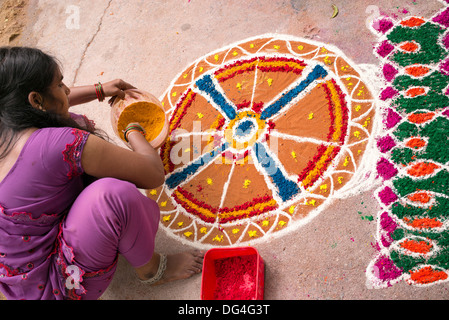 Indian ragazza adolescente rendendo Dasara Rangoli festival di polvere colorata design. Puttaparthi, Andhra Pradesh, India Foto Stock