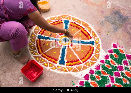 Indian ragazza adolescente rendendo Dasara Rangoli festival di polvere colorata design. Puttaparthi, Andhra Pradesh, India Foto Stock