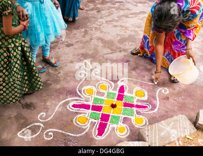 Donna indiana rendendo Dasara Rangoli festival di polvere colorata design. Puttaparthi, Andhra Pradesh, India Foto Stock