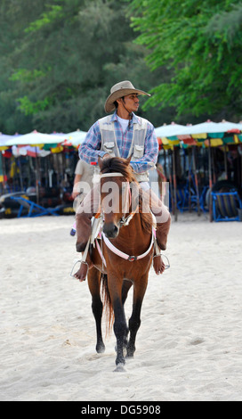 Cavaliere a cavallo sulla spiaggia di Cha Am vicino a Hua Hin in Thailandia. Foto Stock